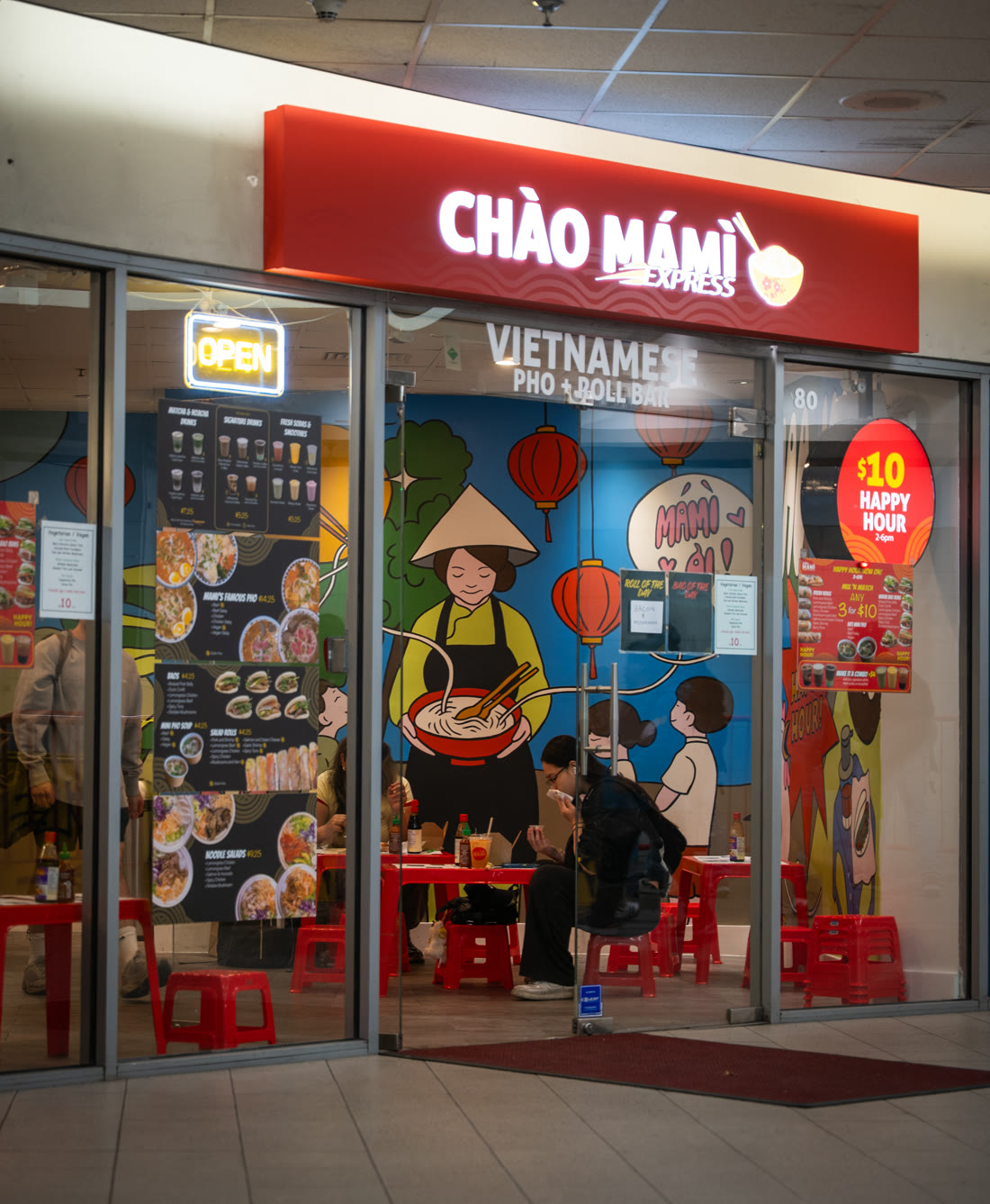 Chào Mámì Express storefront with its mural, red mini stools and tables